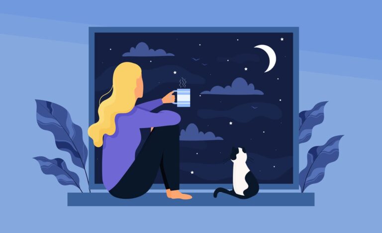 Kvinde sidder med en kop og kigger ud i natten.
