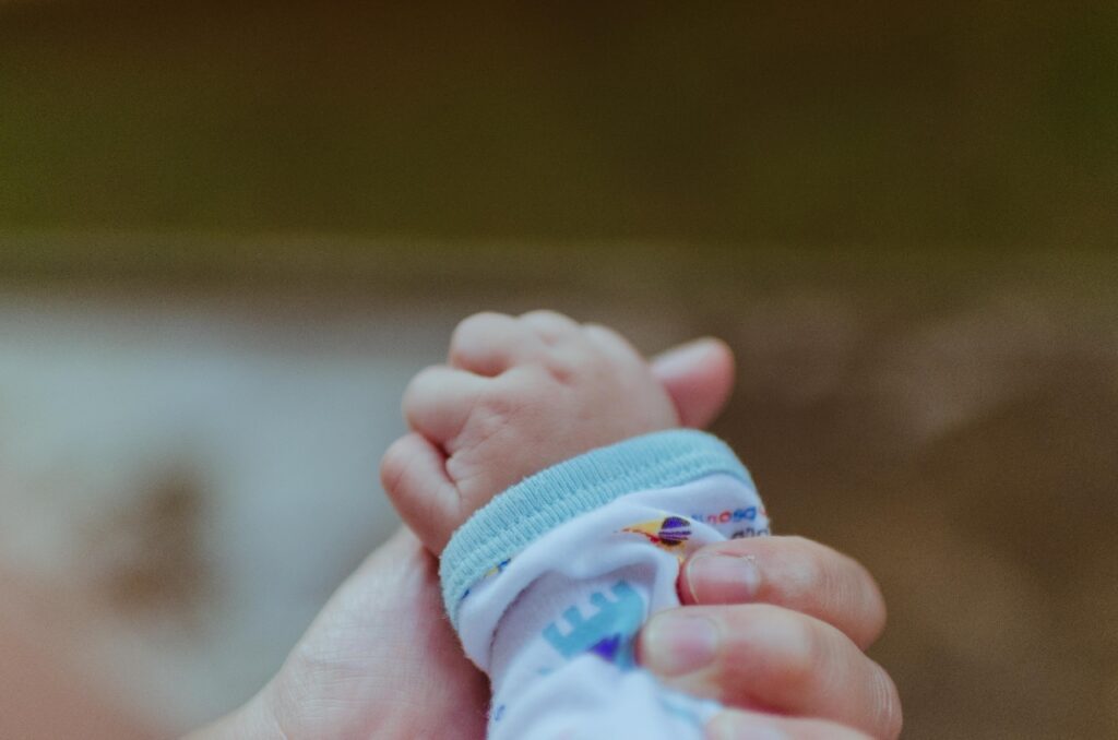 En hånd der holder en babys hånd.