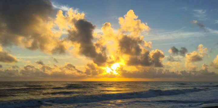 En sol og skyer lige over havet.
